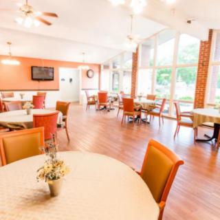 A bright and modern dining area with tables and chairs arranged near large windows.