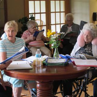 A group of seniors engaged in a reading session together indoors.