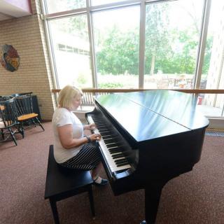 A woman playing the piano in a well-lit room.
