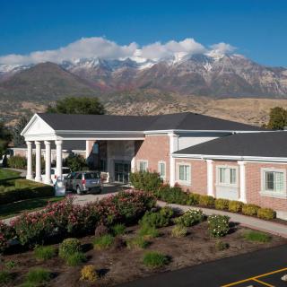 A scenic view of a building with mountains and clouds in the background.