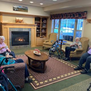 A cozy living room with seniors relaxing near a fireplace.