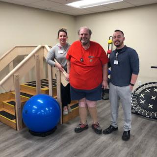 A patient receiving support from healthcare professionals during a physical therapy session.