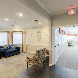 A cozy living room with a seating area adjacent to a well-lit hallway.