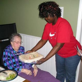 A caregiver serves a meal to an elderly person at an assisted living facility.