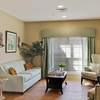A cozy living room with elegant furniture and tasteful decor, featuring a sofa, armchair, coffee table, and window with curtains.