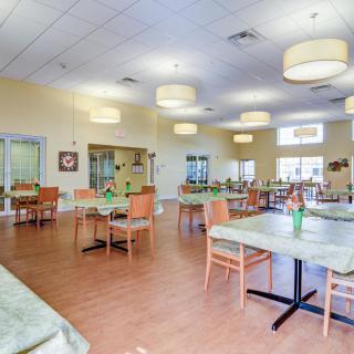 A spacious dining area with neatly arranged tables and chairs, well-lit with modern lighting fixtures.