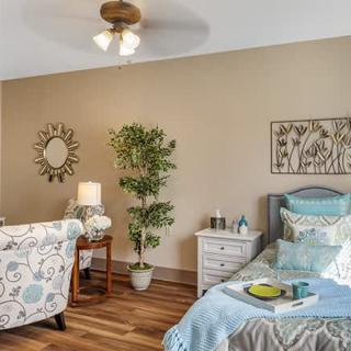 A cozy bedroom with elegant decor including a bed, armchair, and a lamp on a side table.