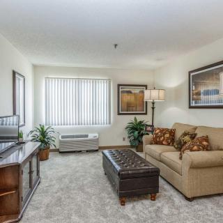 A cozy living room with a sofa, coffee table, TV stand, and decorative artwork.
