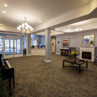 A spacious and elegantly decorated lobby with a piano, chandelier, and seating area.