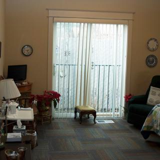 A cozy living room setup with a large window covered by sheer curtains, surrounded by comfortable furniture and decor.