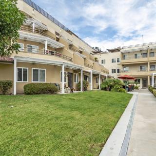 A residential apartment building with balconies overlooking a well-maintained lawn and garden path.