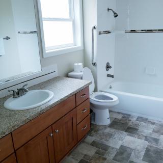 A clean and modern bathroom with a vanity, sink, toilet, and bathtub.