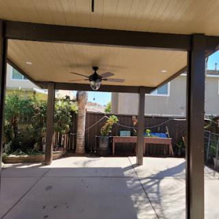 A bright and inviting backyard patio with a ceiling fan, perfect for relaxation.