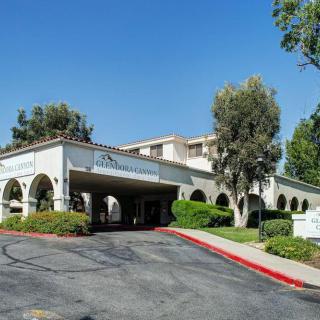 A hotel building with a driveway and arches surrounded by trees.