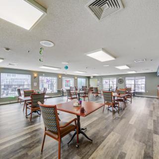 A spacious and modern indoor dining area with several tables and chairs, featuring large windows and stylish flooring.
