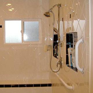 Modern bathroom shower with tiled walls and a grab bar.