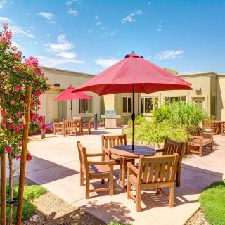 A sunny outdoor patio with wooden furniture and red umbrellas.