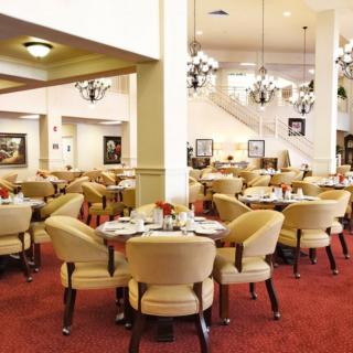 A well-decorated dining area with elegant chandeliers and neatly arranged tables and chairs.