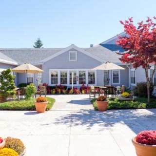 A bright, sunny patio area surrounded by a garden with vibrant flowers and trees.