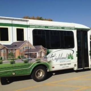 A white bus with a residential advertisement on its side, parked outdoors.