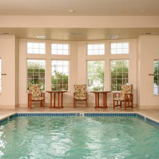 An indoor swimming pool with seating and large windows offering a relaxing atmosphere.