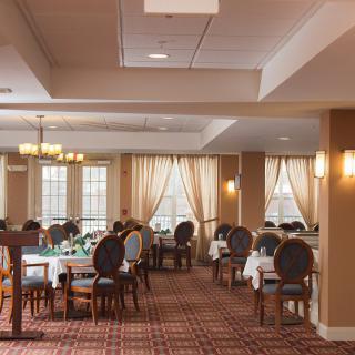 A well-appointed dining room with elegantly set tables and plush chairs, lit by soft ambient lighting.