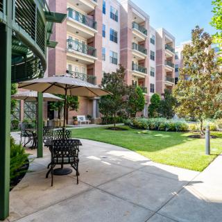 A modern apartment complex with a landscaped outdoor patio area featuring seating and greenery.