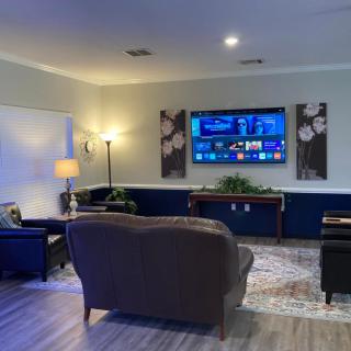 A cozy living room with modern decor, featuring a large wall-mounted TV and comfortable seating.