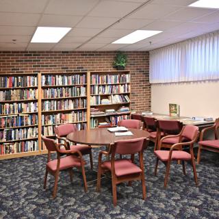 A cozy library corner with bookshelves, a round table, and chairs.