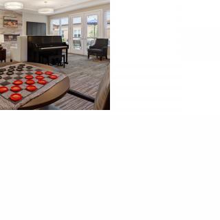 A modern living room with a piano and a large checkers board on the table.