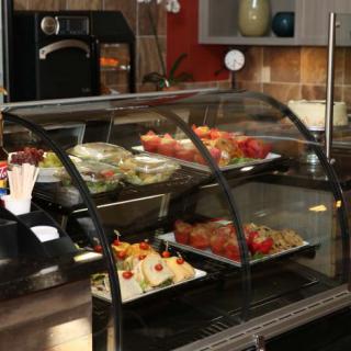 A cafe counter displaying an assortment of desserts and pastries under a glass case.
