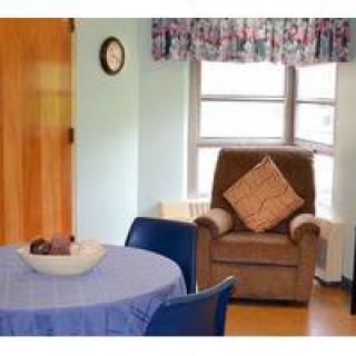 A cozy living room with a comfortable chair and a table covered with a blue tablecloth.