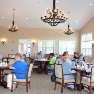 A group of people dining in a well-lit room with chandeliers.