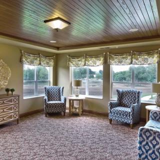 A cozy living room with patterned chairs and large windows.