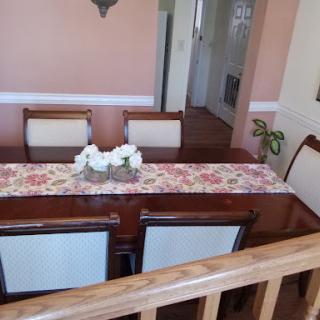A cozy dining room setup featuring a wooden table adorned with a floral centerpiece and comfortable chairs.