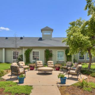 A cozy outdoor patio area with comfortable seating surrounded by greenery.