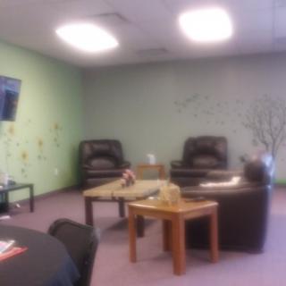 A cozy lounge area with chairs, a coffee table, and a television on the wall.