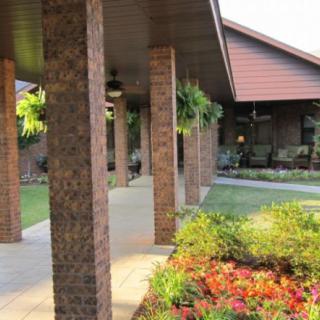 A beautiful brick building with a covered porch and vibrant garden landscape.