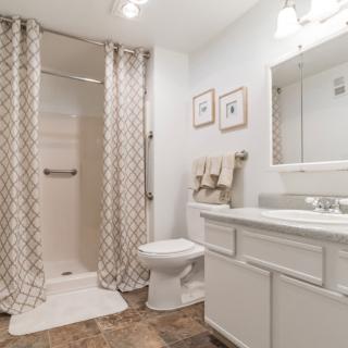 A clean and modern bathroom with a shower, toilet, and sink.
