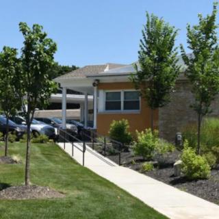 A small building surrounded by greenery with a pathway leading to the entrance.