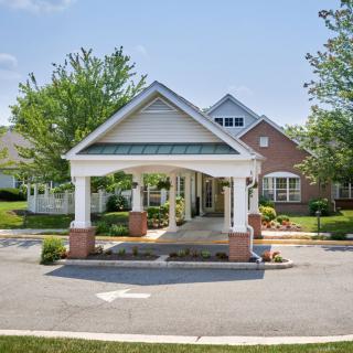 A residential building entrance with a covered driveway and surrounding greenery.