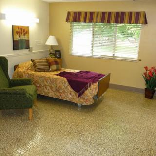 A cozy and well-lit interior space featuring a bed, a green chair, and decorative elements.