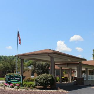 Entrance of a building with an American flag and well-maintained landscaping.