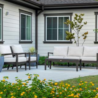 A modern patio with comfortable outdoor seating surrounded by a well-maintained garden.