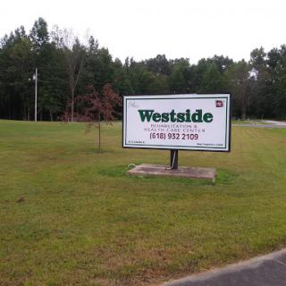 A roadside sign for 'Westside' situated on a grassy area.