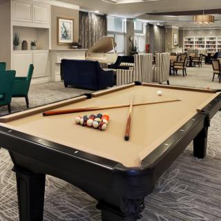 A cozy living room featuring a billiards table with cue sticks ready for a game.