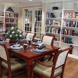 A cozy dining room featuring a set table and bookshelves filled with books.