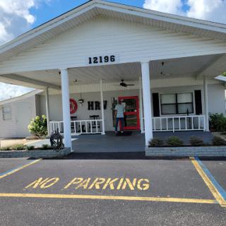 A community center with a 'No Parking' sign visible in front, under a partly cloudy sky.