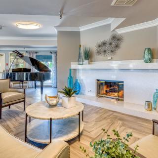 A modern living room featuring elegant furniture, a cozy fireplace, and a grand piano.