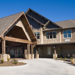 A modern residential building with a prominent entrance and wooden accents under a clear blue sky.